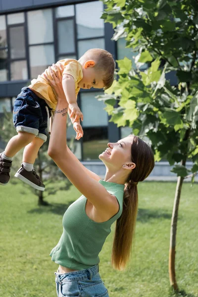 Feliz Madre Sosteniendo Brazos Alegre Hijo Cerca Árbol Verde — Foto de Stock