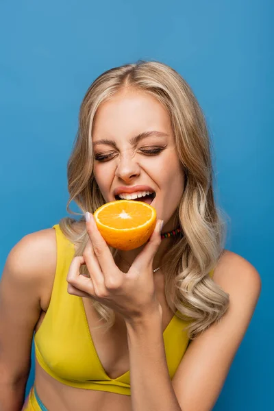 Young Woman Yellow Bikini Top Biting Orange Isolated Blue — Stock Photo, Image