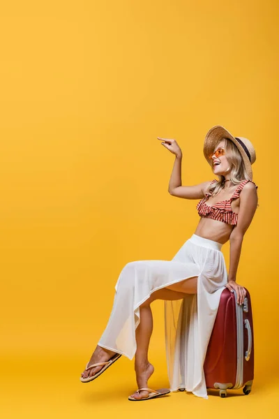 Full Length Happy Woman Sun Hat Sitting Luggage Pointing Finger — Stock Photo, Image