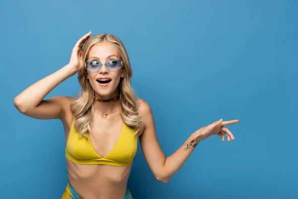 Verbaasd Jonge Vrouw Bikini Top Wijzend Weg Geïsoleerd Blauw — Stockfoto