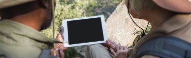 Ormanda ve pankartta dijital tablet kullanan ırklar arası turistlerin kırpılmış görüntüsü 