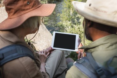 Ormanda dijital tablet kullanan çok ırklı bir çift ön planda bulanık 