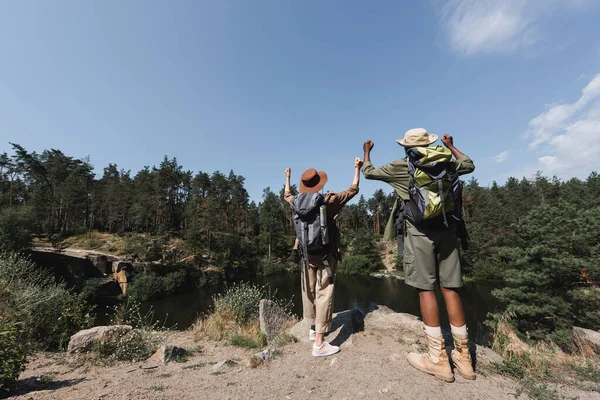 Vista Trasera Excursionistas Multiétnicos Mostrando Mientras Están Pie Roca Cerca —  Fotos de Stock