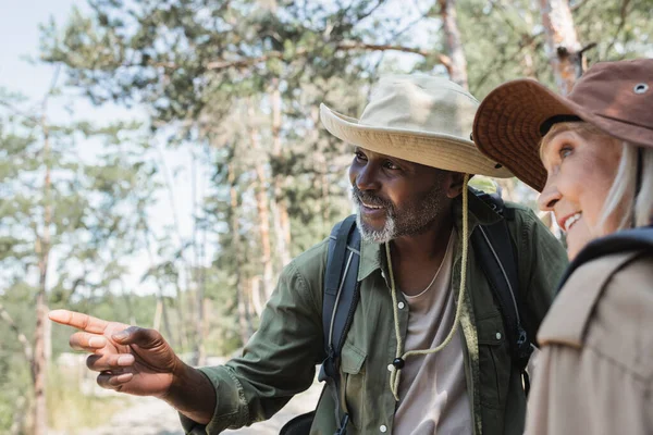 Sorrindo Afro Americano Apontando Com Dedo Perto Esposa Borrada Floresta — Fotografia de Stock