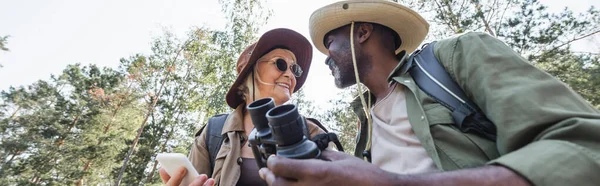 Low Angle View Positive Interracial Tourists Smartphone Binoculars Forest Banner — Stock Photo, Image