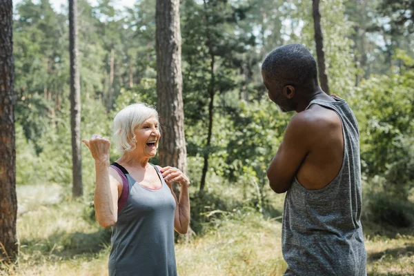 Happy Senior Woman Pointing Finger African American Husband Sportswear Forest — Stock Photo, Image