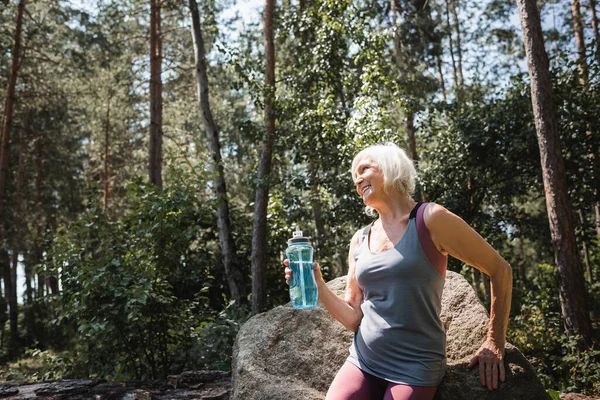 Cheerful Elderly Sportswoman Holding Sports Bottle Stone Forest — Stock Photo, Image