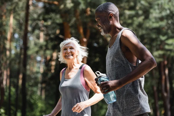 African American Sportsman Holding Sports Bottle While Jogging Wife Forest — Stock Photo, Image