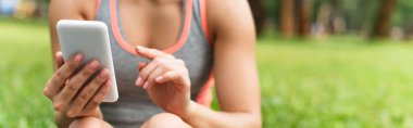 Parkta akıllı telefon kullanan sporcu kadın manzarası, afiş