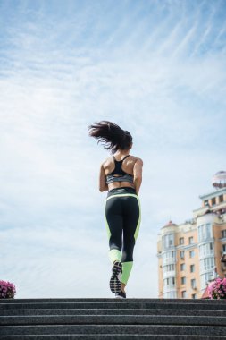 Kentsel caddede koşan sportif kadının arka plan görüntüsü 