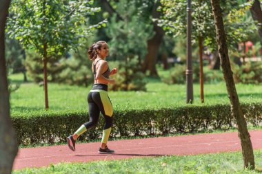 Yeşil Park 'ta kablosuz kulaklıklı, gülümseyen bir sporcu kadın.