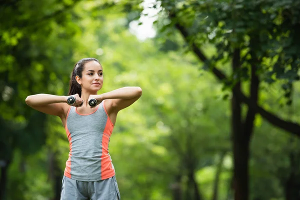 Fiatal Sportnő Néz Félre Edzés Közben Súlyzókkal Parkban — Stock Fotó