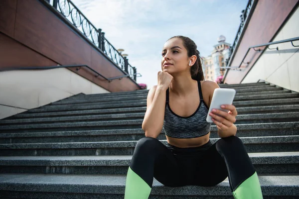 Young Sportswoman Wireless Earphones Using Smartphone While Listening Music Sitting — Stock Photo, Image