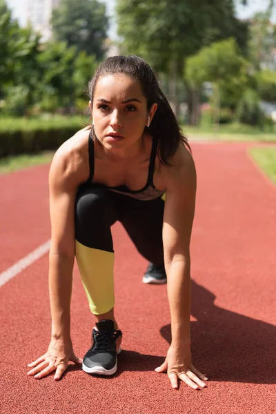 Atletická Žena Bezdrátových Sluchátkách Stojící Počáteční Póze Stadionu — Stock fotografie