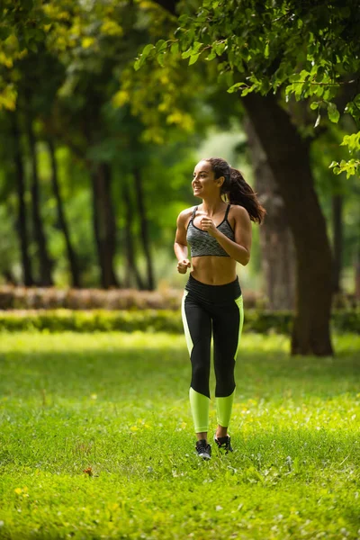 Full Lengde Positiv Sportskvinne Vekselbruk Leggbeskyttere Som Jogger Gress Parker – stockfoto