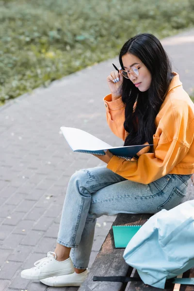 Asiatico Studente Cercando Notebook Mentre Seduta Panchina Parco — Foto Stock