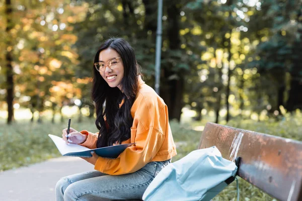 Boldog Ázsiai Írás Notebook Mosolygós Kamera Padon Parkban — Stock Fotó