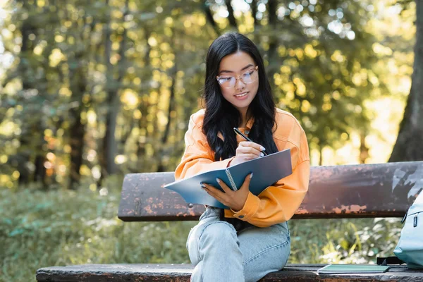 Positiver Asiatischer Student Sitzt Auf Bank Park Und Schreibt Notizbuch — Stockfoto