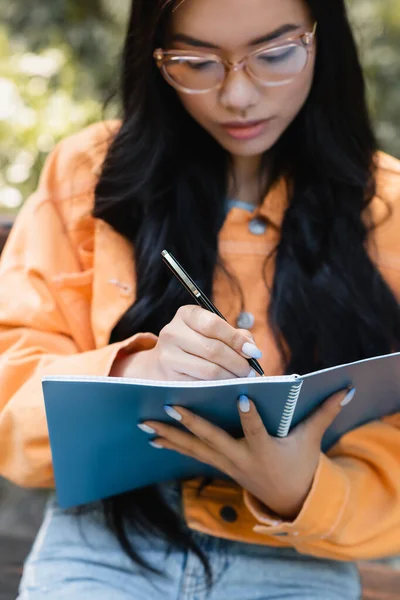 Flou Asiatique Femme Dans Lunettes Écriture Dans Notebook Extérieur — Photo