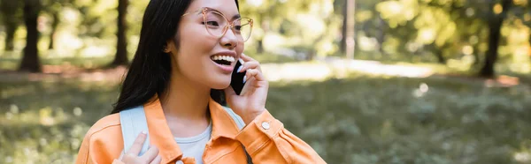 Excitada Mujer Asiática Gafas Hablando Teléfono Inteligente Parque Pancarta — Foto de Stock