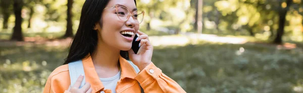 Opgewonden Aziatische Vrouw Bril Praten Smartphone Park Banner — Stockfoto