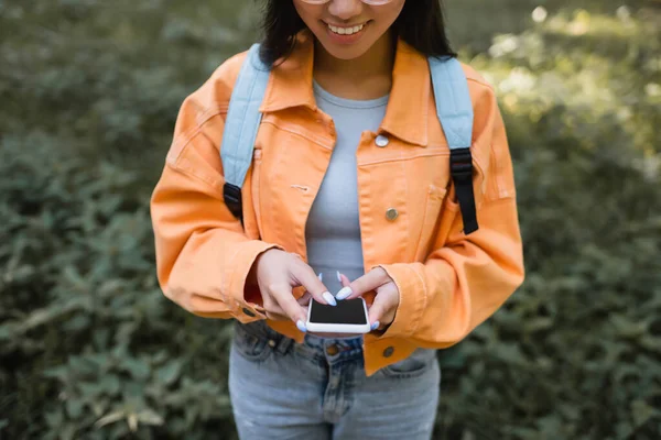 薄型画面の携帯電話を使ってオレンジのジャケットの笑顔の女性のクロップドビュー — ストック写真