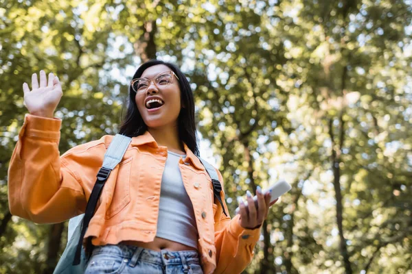 Vedere Unghi Scăzut Studentului Asiatic Excitat Rucsac Mână Fluturând Smartphone — Fotografie, imagine de stoc