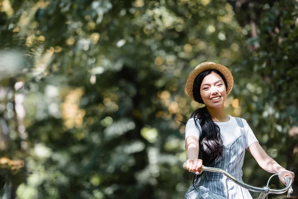 Glad Asiatisk Kvinna Halmhatt Ler Mot Kameran När Cyklar Parken — Stockfoto