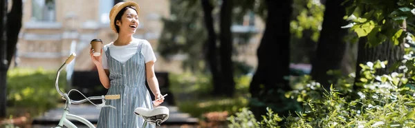 Joven Asiático Mujer Con Celular Papel Taza Riendo Cerca Bicicleta — Foto de Stock