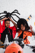 afro-amerikai gyerekek halloween jelmezben főzetet készítenek boszorkányüstben.