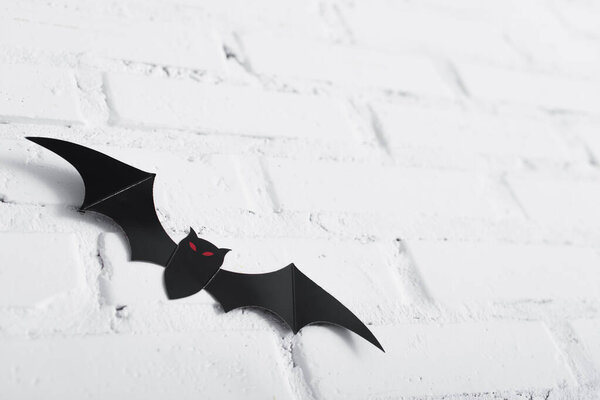 paper cut bat on white brick wall 