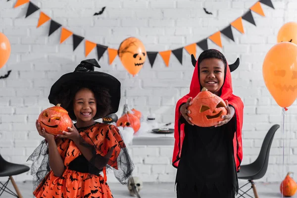 Crianças Americanas Africanas Alegres Trajes Halloween Segurando Abóboras Esculpidas Casa — Fotografia de Stock