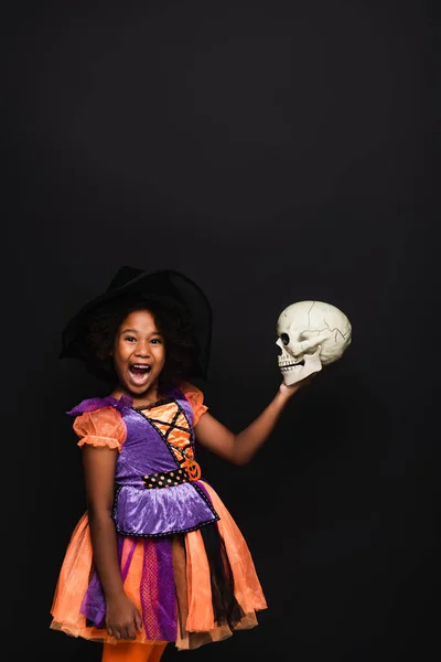 Amazed African American Girl Witch Halloween Costume Holding Skull Isolated — Stock Photo, Image