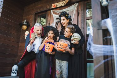 Cadılar Bayramı kostümü içinde oyuncak el tutan ve ailenin yanında yüzünü buruşturan bir adam.