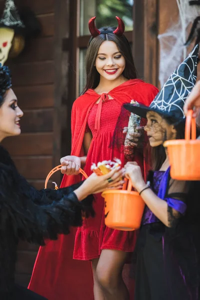 Mom Giving Candies Happy Daughters Devil Witch Halloween Costumes — Stock Photo, Image