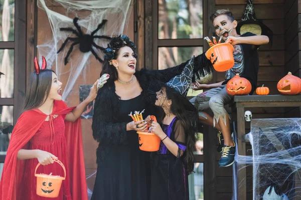 Vzrušená Žena Dětmi Strašidelných Kostýmech Kbelíky Sladkostí Verandě Halloween Dekorací — Stock fotografie