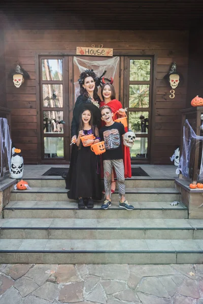 Šťastná Rodina Děsivých Kostýmech Kbelíky Sladkostí Chalupě Verandě Halloween Dekorace — Stock fotografie