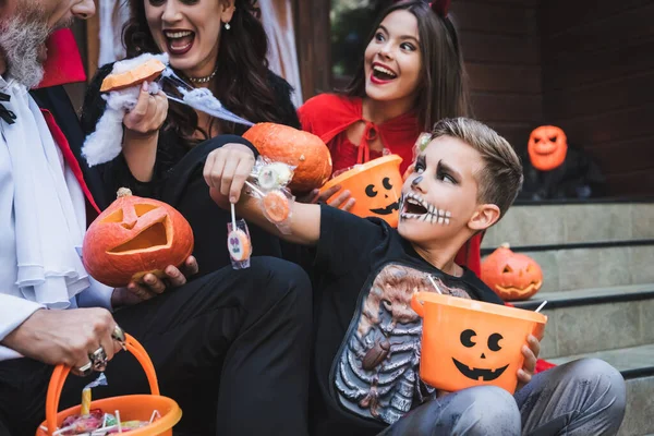 Vzrušený Chlapec Drží Lízátka Blízkosti Rodiny Halloween Kostýmy — Stock fotografie