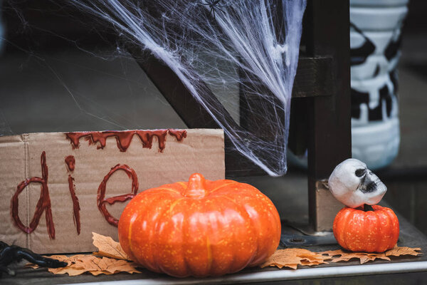 pumpkins, skull and autumn leaves near card with die lettering on decorated porch