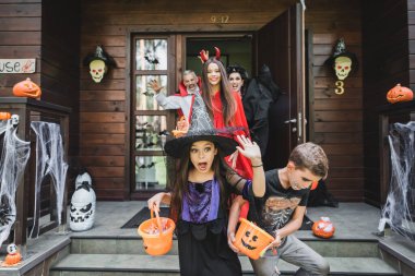 Cadılar Bayramı kostümü giymiş korkmuş çocuklar, ürkütücü komşulardan kaçarken çığlık atıyorlar.