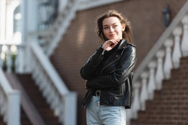 都会の通りに立つ黒い革のジャケットの幸せな若い女性 — ストック写真