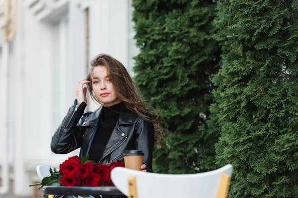 Vacker Kvinna Läder Jacka Håller Pappersmugg Nära Bukett Röda Rosor — Stockfoto