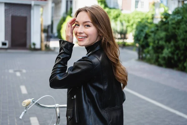 Mujer Joven Complacida Ajustando Pelo Cerca Bicicleta Calle Urbana Europa — Foto de Stock