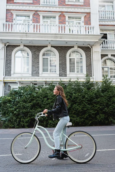 ヨーロッパの都会の通りで自転車に乗る喜びとスタイリッシュな女性の完全な長さ — ストック写真