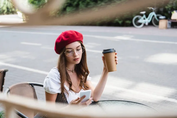 Young Woman Red Beret Eyeglasses Holding Paper Cup Using Smartphone — Stock Photo, Image