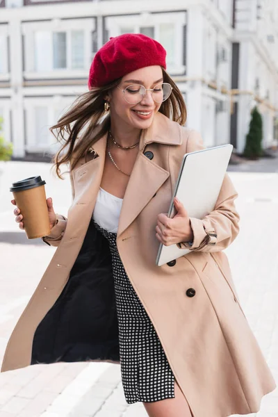 Alegre Freelancer Boina Roja Gabardina Beige Sosteniendo Laptop Taza Papel — Foto de Stock