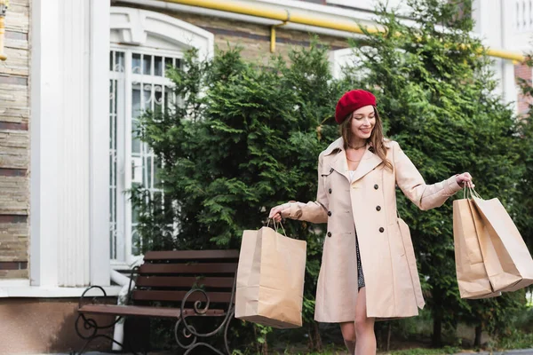 Mujer Alegre Boina Roja Gabardina Beige Sosteniendo Bolsas Compras Calle —  Fotos de Stock