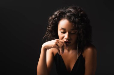 Genç Afrikalı Amerikalı kadın aşağı bakıyor ve siyahlara poz veriyor.