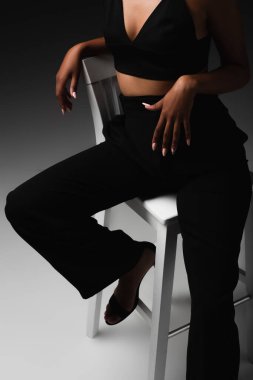 Beyaz sandalyede oturan saten bluzlu seksi Afro-Amerikan kadın manzarası. 