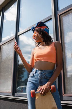 Afro-Amerikan kadın türbanlı, uzun pano ve akıllı telefonu dışarıda tutuyor. 